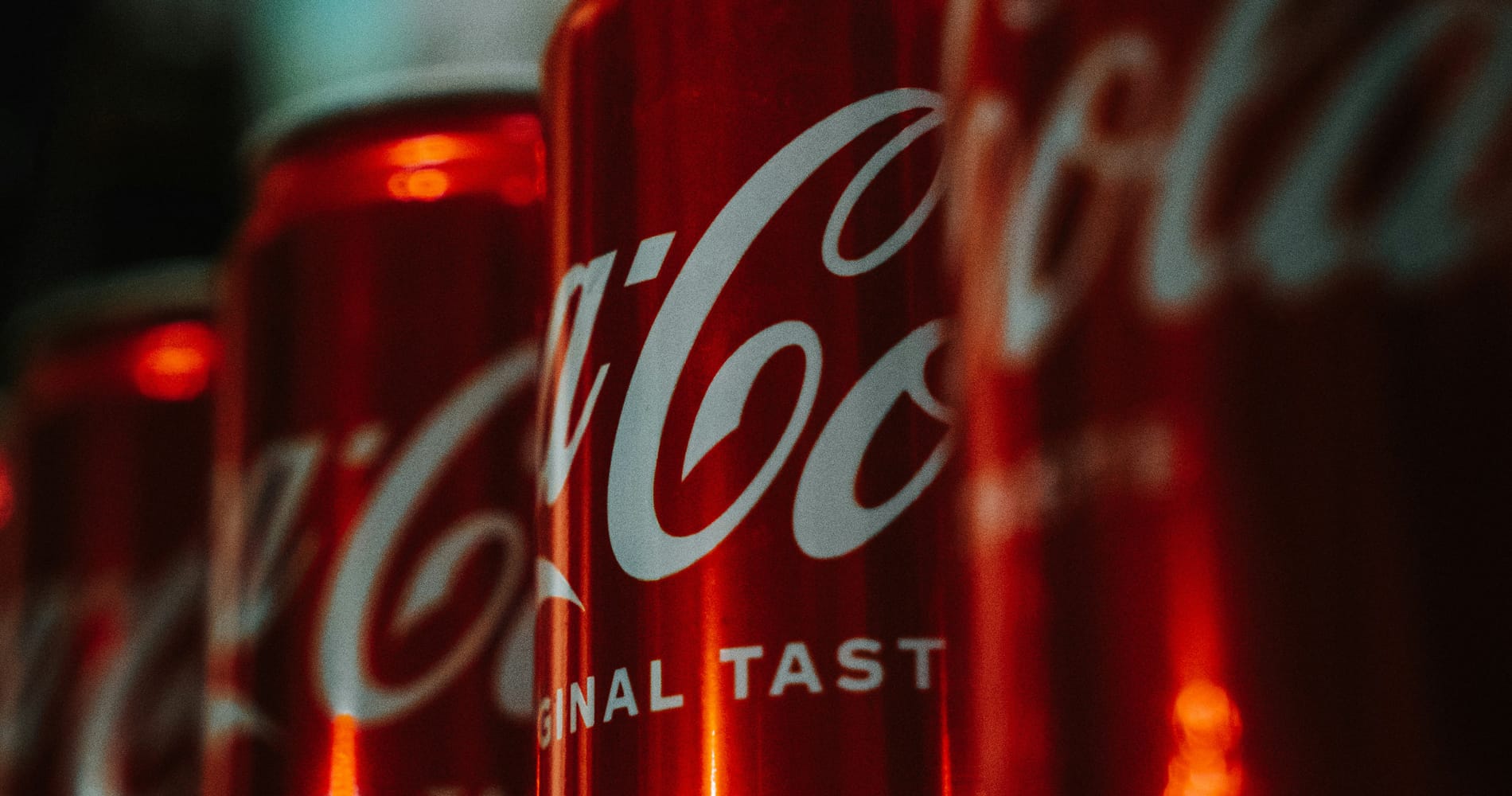Coca Cola’s classic script logo on 4 cans lined up