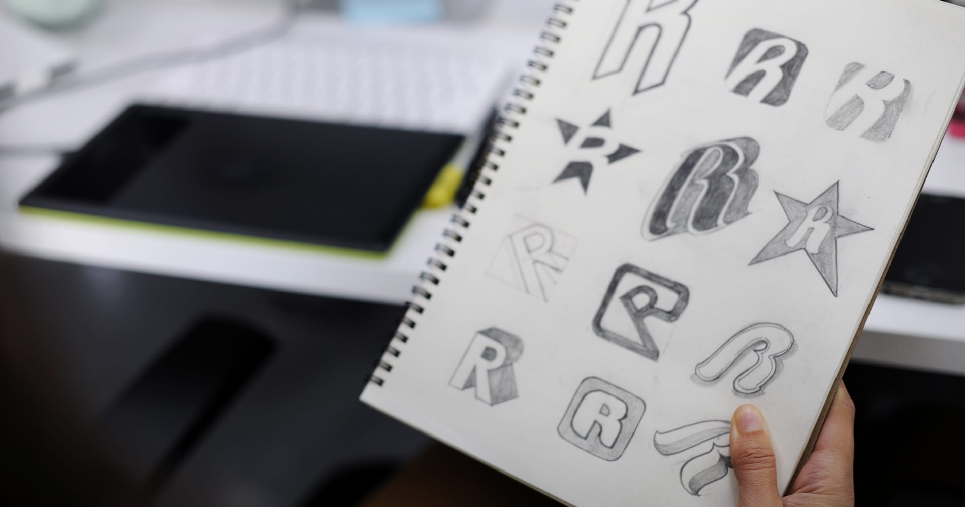 Hand Holding Notebook With Brand Logo Design Ideas for the letter R